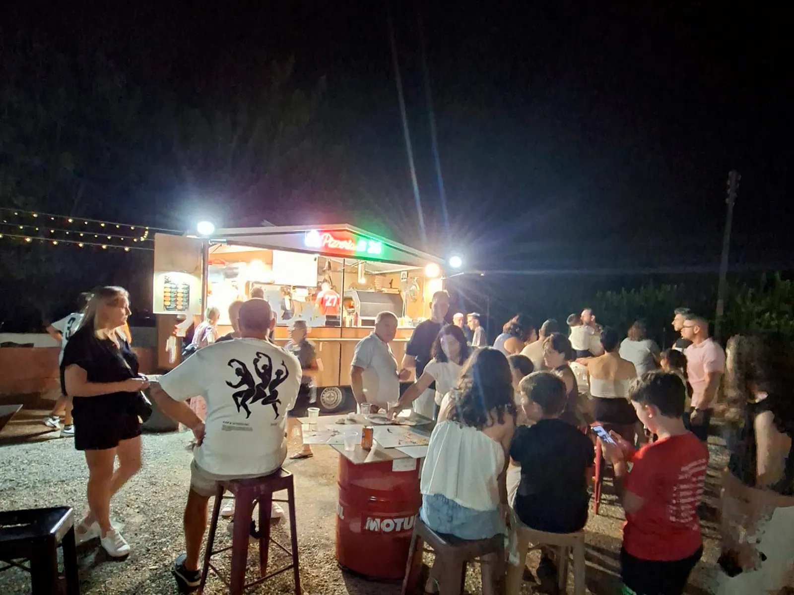 El food truck de Pizzería El 26 de noche en Murcia, iluminado y con las mesas ocupadas